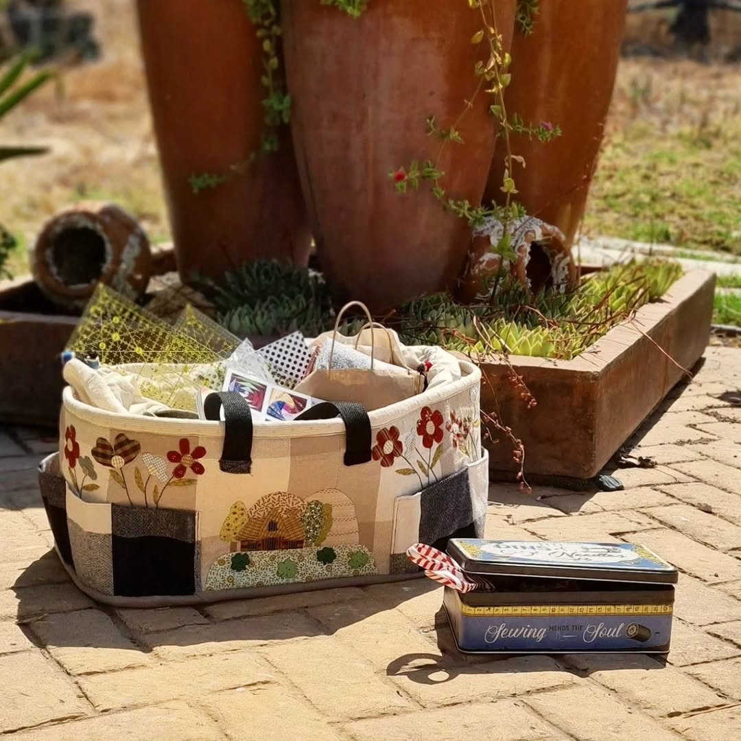 Cesta costurero de patchwork con flores y casita aplicadas, llena de materiales de costura